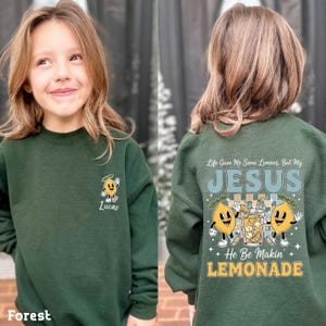 Personalized Jesus Lemonade Shirt with happy lemon graphics and the quote “Life Gave Me Some Lemons, But My Jesus He Be Makin’ Lemonade” — cute faith based kids sweatshirt and Christian shirt.