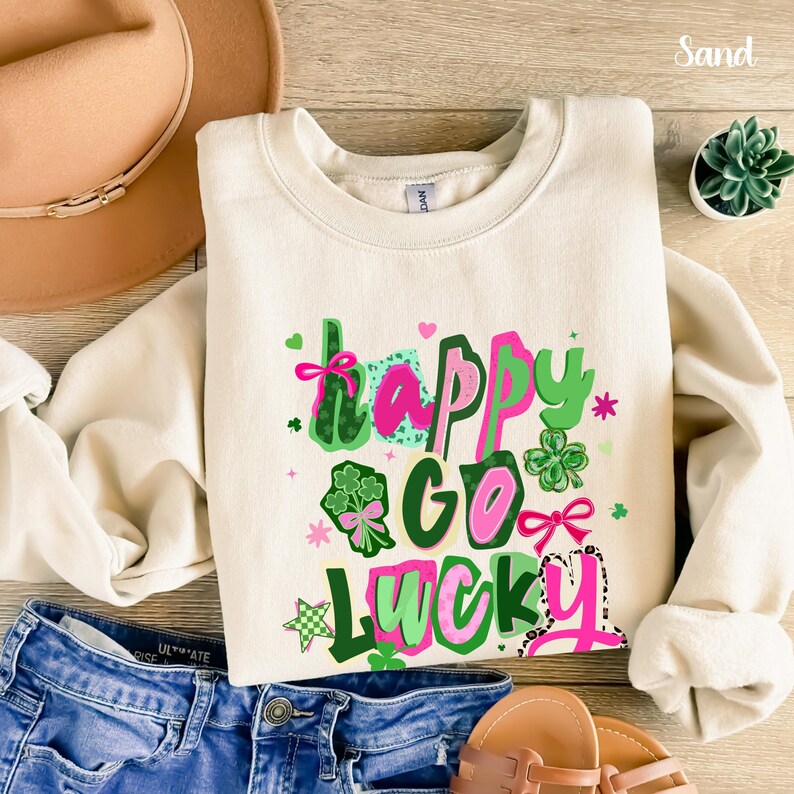 a white sweatshirt with a colorful graphic design, a pair of jeans, a hat, and a small potted plant.