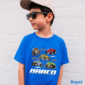 A young boy wearing a blue t-shirt with a graphic of monster trucks and the name "MARCO" printed on it.