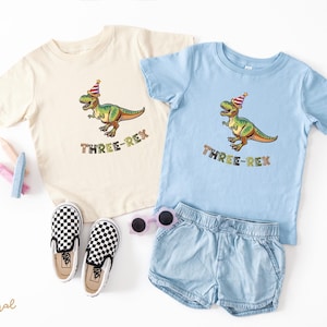 Dinosaur-themed family birthday shirts including a Three Rex or Four Rex kids tee with name and age on back, plus matching Mama Saurus, Dada Saurus, and sibling designs — ideal for dinosaur birthday parties.
