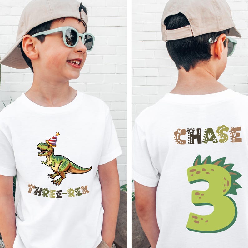 A young boy wearing a white t-shirt with a dinosaur graphic and the text "Three Rex" printed on it.