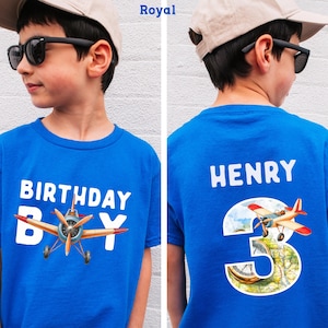 A boy wearing a blue t-shirt with a graphic of a propeller plane and the text "Birthday Boy" printed on it.