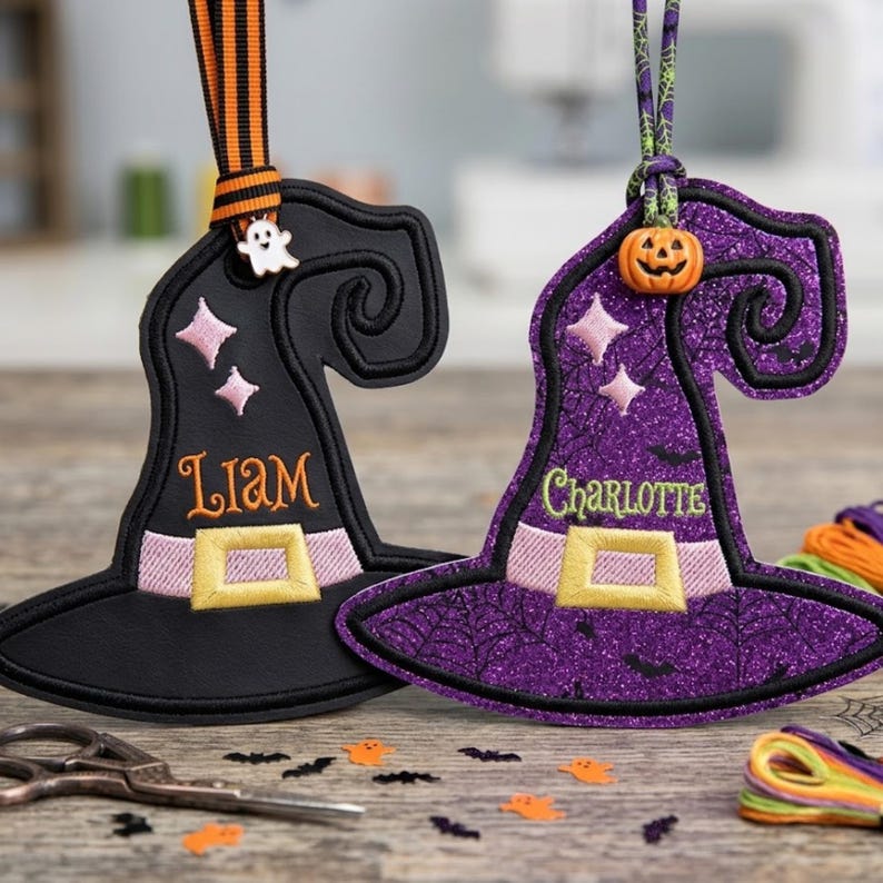May include: Two witch hat ornaments featuring embroidered details. The black hat has the name Liam, a ghost charm, and orange-striped ribbon. The purple glitter hat has the name Charlotte, a pumpkin bead, and a green spiderweb-patterned ribbon.