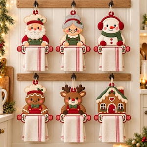 May include: Six decorative fabric towel holders featuring embroidered holiday characters including Santa, Mrs. Claus, a snowman, a gingerbread person, a reindeer, and a gingerbread house, each holding a white kitchen towel with red stripes.