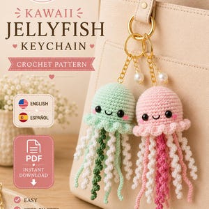 May include: Two crocheted jellyfish keychains, one mint green and one light pink, each with black eyes and pink cheeks. They feature dangling curly tentacles in matching colors and white, attached to gold-tone metal rings with pearl accents.