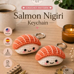 May include: A digital crochet pattern for a Salmon Nigiri keychain by Amibloom by G. The pattern features two crocheted sushi pieces with orange tops, white rice bases, black eyes, and pink cheeks, each attached to a silver metal keyring.