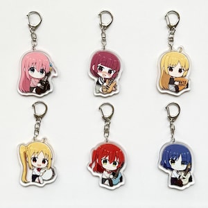 Puede incluir: Seis llaveros de estilo anime con personajes coloridos con guitarras. Cada llavero tiene un anillo y un cierre de color plateado. Los personajes tienen diferentes colores de pelo, incluyendo rosa, rojo, amarillo y azul, y visten varios atuendos.