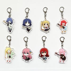 Puede incluir: Ocho llaveros de estilo anime con personajes con guitarras. Cada llavero tiene un anillo plateado y un dije de acrílico transparente con un diseño de personaje diferente. Los personajes tienen varios colores de cabello, incluyendo azul, amarillo, rosa y rojo.