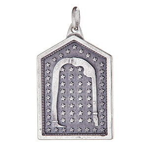 May include: A silver pendant shaped like a house with a background of stars and a stylised figure of a person bending backwards inside the house.