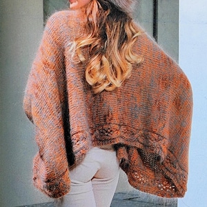 May include: An orange and gray knit poncho with a decorative hem, paired with light-colored pants and tall brown suede boots. A fur hat completes the look. The outfit is suitable for fall or winter.
