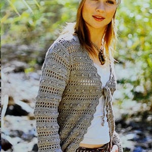 Könnte beinhalten: Hellbraune Häkeljacke mit offenem Schnitt, langen Ärmeln und Bindeband. Die Jacke wird mit braunen Cordhosen und einem weißen Oberteil kombiniert. Ein gemustertes Stirnband und eine Halskette vervollständigen den Look. Geeignet für einen lässigen, böhmischen Stil.