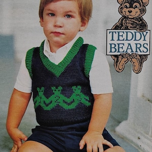 Puede incluir: Un niño pequeño con un chaleco de punto azul marino y verde sobre una camisa blanca y pantalones cortos azul marino. El chaleco presenta un diseño de oso de peluche verde. Un oso de peluche de dibujos animados sosteniendo un letrero que dice "TEDDY BEARS" en el fondo.