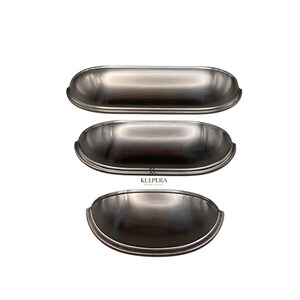 Könnte beinhalten: Drei Schrankgriffe aus gebürstetem Nickel in verschiedenen Größen werden vor einem weißen Hintergrund gezeigt. Die Griffe haben ein gebogenes, becherartiges Design mit glatter, metallischer Oberfläche. Das KULPERA-Logo ist sichtbar.