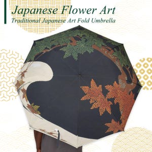 May include: A traditional Japanese art fold umbrella with a black background and a design featuring a tree with green leaves and orange leaves. The umbrella has the text "Japanese Flower Art" and "Traditional Japanese Art Fold Umbrella".