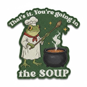 Könnte beinhalten: Gestickter Aufnäher mit einem Froschkoch, der Suppe in einem Topf umrührt. Der Frosch trägt eine Kochmütze und Schürze, mit dem Text "That's it. You're going in the SOUP" in Weiß auf grünem Hintergrund.