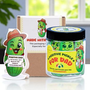 May include: A gift set featuring a jar of "Positive Pickle for Dad" candies, a cardboard box, and a pickle-shaped card. The jar has a black lid and a yellow label. The card reads "Positive Dad, I may be small, but I believe in your strength! You're rocking this!"