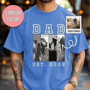 May include: A blue t-shirt with the word "DAD" in white block letters above a series of black and white photos. The shirt also features the text "EST. 2025" and a small photo with the text "YOUR PHOTO".