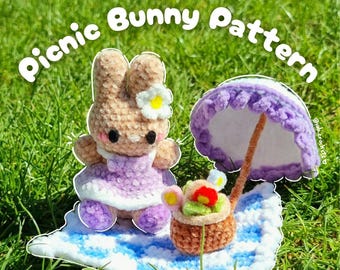 May include: A crocheted bunny wearing a purple dress and a flower in its ear sits on a blue and white blanket. A miniature picnic basket and a purple umbrella are also present. The text "Picnic Bunny Pattern" is displayed.