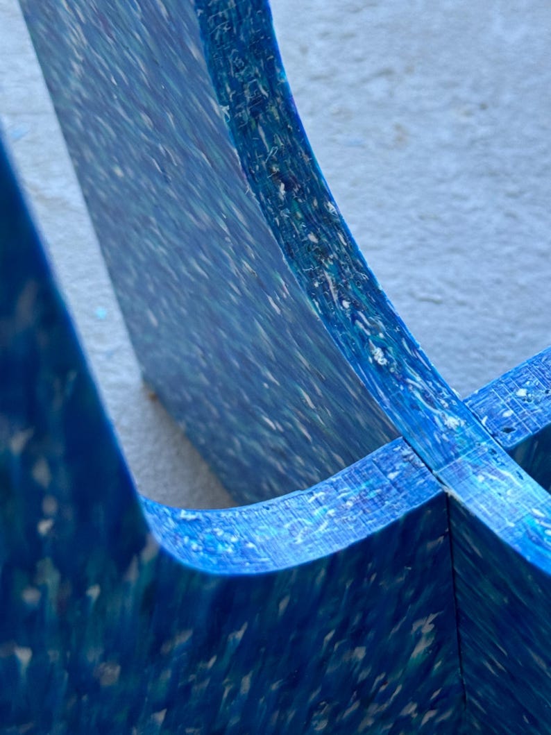 May include: Close-up of a section of a blue, multi-layered object with a speckled pattern. The object has a curved shape and appears to be made of a composite material. The color palette includes shades of blue and white.