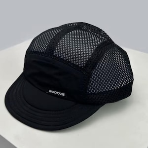 Könnte beinhalten: Schwarze Mesh-Kappe mit gebogenem Schirm. Die Kappe hat eine schwarze Front und einen Schirm, mit dem Text "WASCHOUSE" auf der Vorderseite. Die Oberseite der Kappe besteht aus atmungsaktivem Mesh-Material.