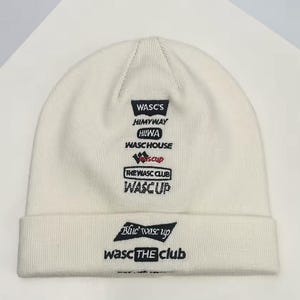Pode incluir: Um gorro branco com vários logotipos bordados em preto. Os logotipos incluem texto como "WASC'S", "HIMYWAY", "HILWA", "WASCHOUSE", "WASCUP" e "THE WASC CLUB". O gorro tem uma textura canelada.