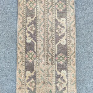 Peut inclure: Un tapis rectangulaire de style vintage avec un aspect vieilli. Le tapis présente un motif central de rayures verticales dans des tons de marron et de beige, avec des motifs floraux et géométriques. Les bords sont décolorés.