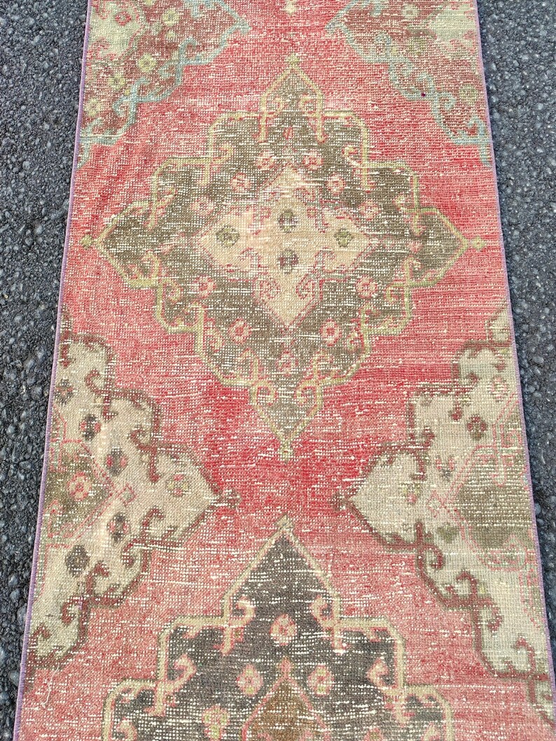 May include: A rectangular, distressed rug with a central medallion design. The rug features a faded red background with accents of brown, beige, and teal. The pattern is geometric and traditional, suitable for home decor.