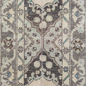 May include: A rectangular, vintage rug with a central medallion design. The rug features a palette of beige, brown, and muted teal. The pattern includes floral and geometric elements, creating a distressed, antique appearance. Suitable for home decor.