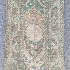 Könnte beinhalten: Ein rechteckiger Teppich im Vintage-Stil mit einem Used-Look. Der Teppich hat ein zentrales Design in Beige-, Braun- und Türkistönen mit geometrischen und floralen Mustern. Die Ränder sind mit einem Streifendesign in ähnlichen Farben eingefasst.