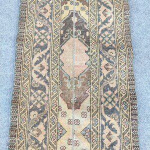 Könnte beinhalten: Ein rechteckiger Teppich im Vintage-Stil mit einem zentralen Design in Braun-, Beige- und Rosatönen. Der Teppich weist komplizierte Muster und Bordüren in gedämpften Blau-, Grün- und Goldtönen auf und erzeugt ein klassisches, gealtertes Aussehen.