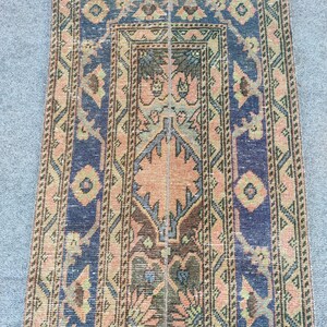 Könnte beinhalten: Ein rechteckiger Vintage-Teppich mit einem zentralen Design in Pfirsich, Braun und Grün, umrahmt von marineblauen Bordüren. Der Teppich weist komplizierte geometrische und florale Muster auf.