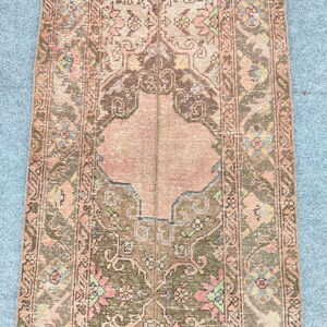 May include: A rectangular, vintage-style rug with a central medallion design. The rug features a palette of muted colors, including shades of brown, peach, and olive green. Intricate floral and geometric patterns adorn the rug's surface, creating a distressed, antique appearance.