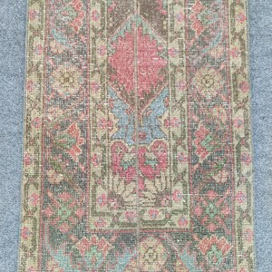 Peut inclure: Tapis rectangulaire vintage avec un motif central en losange dans les tons de rouge, marron et bleu. Le tapis présente des motifs floraux et une bordure dans des tons vert et beige. Le design du tapis a un aspect vieilli et antique.