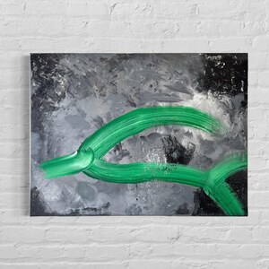 Könnte beinhalten: Abstrakte Malerei auf Leinwand mit einem grünen, geschwungenen Pinselstrich vor einem grau-schwarzen Hintergrund. Das Kunstwerk ist an einer weißen Backsteinmauer befestigt.