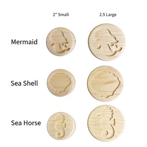 May include: A set of round wooden stamps featuring engraved designs of a mermaid, a sea shell, and a sea horse. The stamps are labeled 2" Small and 2.5" Large, showing two size variations for each of the three distinct ocean-themed motifs.