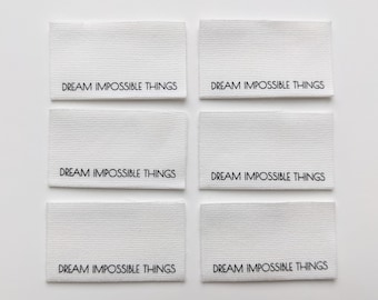 May include: Six white fabric labels with the text "DREAM IMPOSSIBLE THINGS" printed in black.