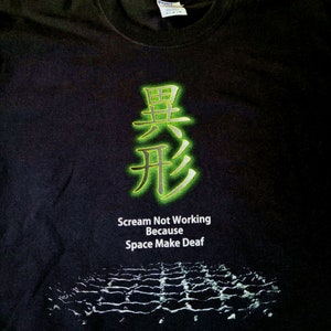 May include: Black t-shirt with a green and gold Chinese character and the text "Scream Not Working Because Space Make Deaf".