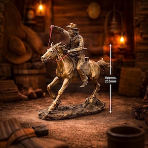 Puede incluir: Una escultura de color bronce de un vaquero montando a caballo, con una rienda roja. La escultura mide aproximadamente 21,5 cm de altura. El vaquero lleva un sombrero y sujeta la rienda. El caballo está en movimiento y la escultura está sobre una base.