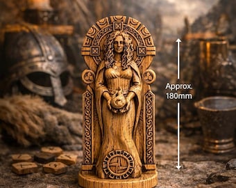 May include: A wooden statue of a woman, approximately 7 inches tall, holding a sphere. The statue has intricate carvings and is set against a blurred background with a candle and helmet. The statue is a representation of Norse mythology.