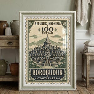 Könnte beinhalten: Ein gerahmter Wandkunstdruck mit einem Briefmarkendesign im Vintage-Stil des Borobudur-Tempels in Indonesien. Der Druck zeigt den Text REPUBLIK INDONESIA, 100 RUPIAH, BOROBUDUR und YOGYAKARTA in einer gedämpften grün-cremefarbenen Farbpalette.