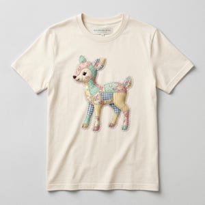 May include: A cream-coloured t-shirt with a patchwork deer design. The deer is made from various fabric patterns, including floral, gingham, and solid pastel colours. The shirt has a crew neck and short sleeves. The brand name "PATCHWORK REVEL" is printed on the shirt.