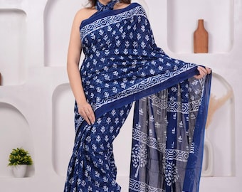 Può includere: Un sari blu navy con un motivo floreale bianco e un bordo geometrico. Il sari è drappeggiato sul corpo, con una sciarpa abbinata intorno al collo. Il tessuto sembra leggero e fluido.