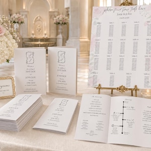 May include: A collection of wedding stationery, including programs, a seating plan, and ceremony booklets. The programs and booklets feature a floral design and the names "Jane & John". The seating chart is on a gold easel with the text "please find your table here".