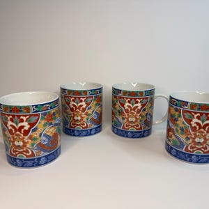 Puede incluir: Cuatro tazas de cerámica con un diseño colorido y ornamentado. Las tazas tienen un interior blanco, una base azul y un asa. El exterior está decorado con motivos florales y de dragones rojos, amarillos y azules.