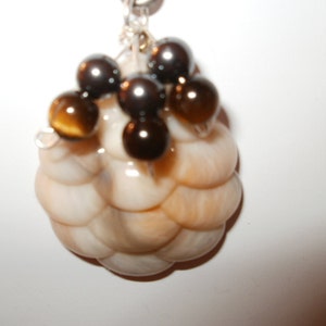 May include: A white and brown shell-shaped pendant with brown and black beads hanging from it.