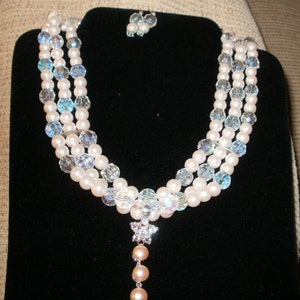 May include: A three-strand pearl and crystal necklace with a crystal pendant and a matching pair of earrings.