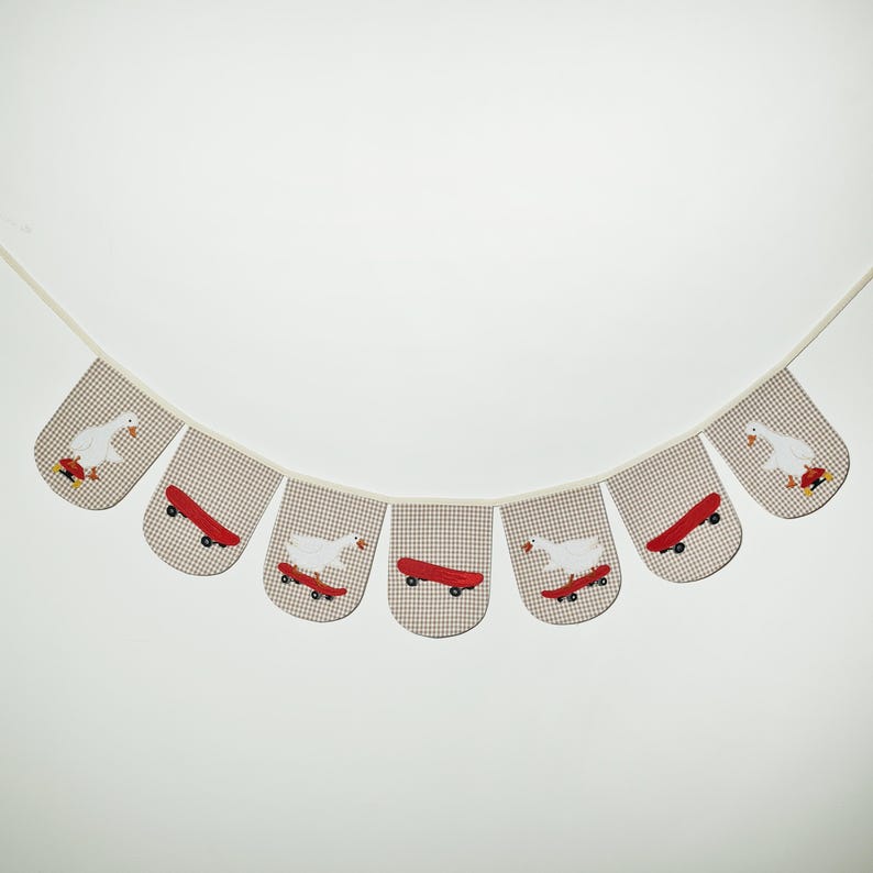 Fun goose nursery decor with white goose skateboard appliques on beige mini-check, handmade garland and kids room bunting