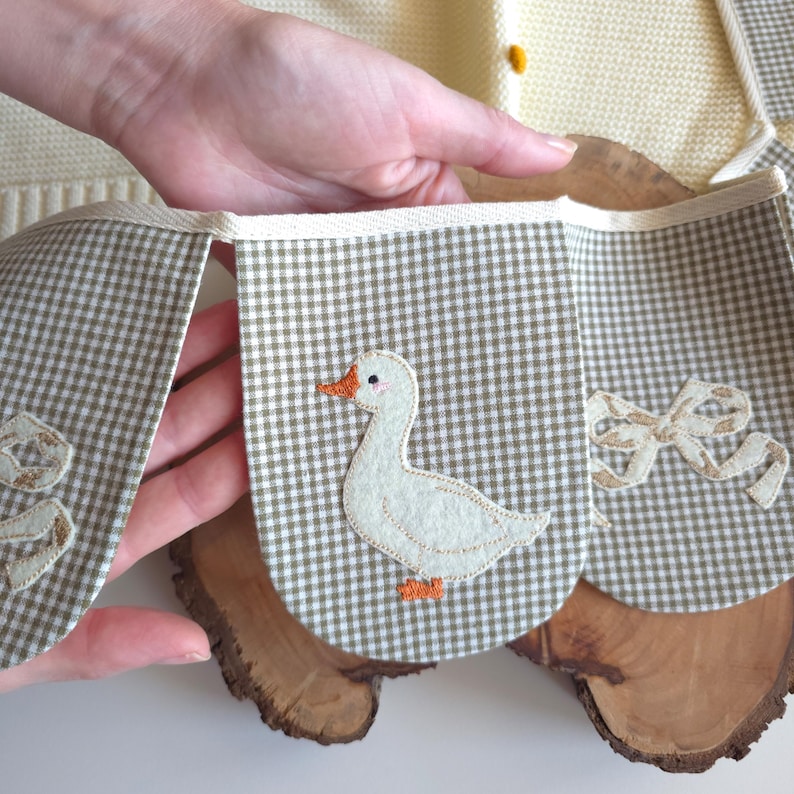 White goose garland made of cotton flags with felt geese in blue hats on wavy orange ovals, hanging on nursery wall, perfect goose nursery decor, baby room garland, handmade garland.
