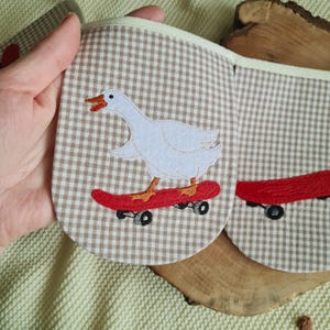 Light beige checkered kids room bunting with white geese on skateboards, whimsical goose garland and handmade garland for a modern nursery.