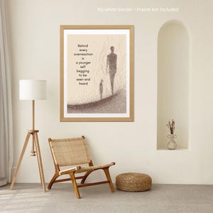 May include: A framed art print with a minimalist illustration of two figures on a path, with the text "Behind every overreaction is a younger self begging to be seen and heard." The frame is light brown.